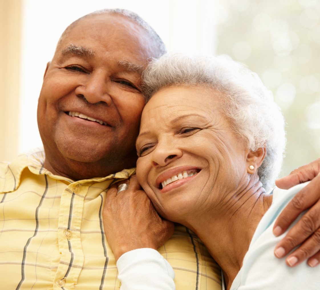 elderly couple smiling and holding each other