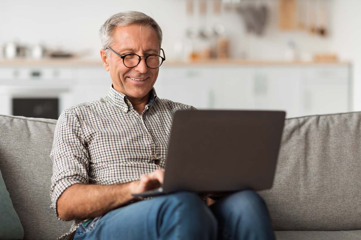 smiling elderly man looking at a laptop