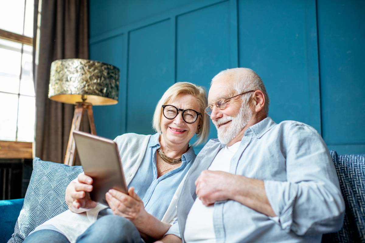 smiling elderly couple looking at a tablet